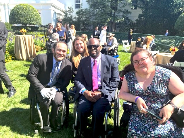 A big group of disability rights advocates at a banquet in the white house rose garden.
