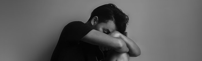 Photo of a depressed man with his head between his knees.
