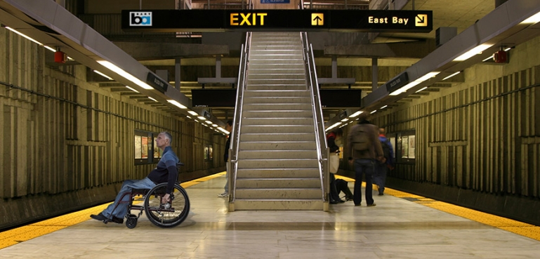 Photo of man in wheelchair waiting for a BART train at a station