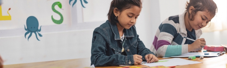 Two young girls doing homework in a classroom