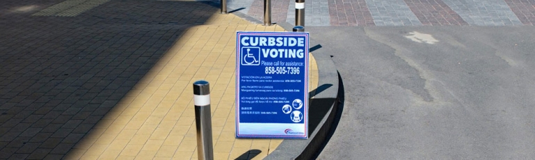A curbside voting sign on the side of the road.