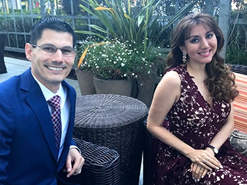 David and his wife sitting next to each other smiling.  