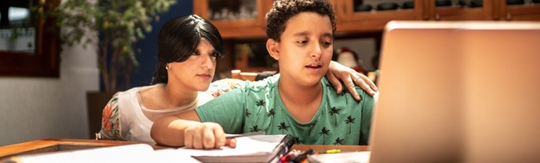 A young boy with an intellectual disability trying to learn at home. His mom is trying to help him.