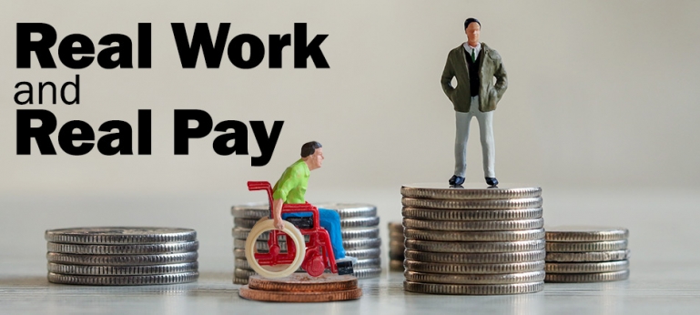 Real Work and Real Pay - Photo of photo of a figure of a man in a wheelchair on top of two pennies along side a figure of a business man on top a stack of qaurters