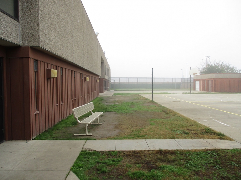 Bench outside the detention center with a chain-link fence in the background.