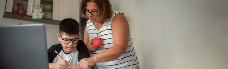 A Latinx mother helping her son with schoolwork at home