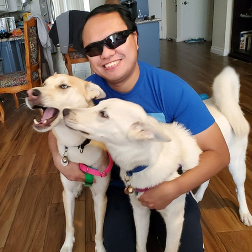 Raymond smiling and posing with their 2 beautiful husky-shepherd mixes Artemis & Iris.