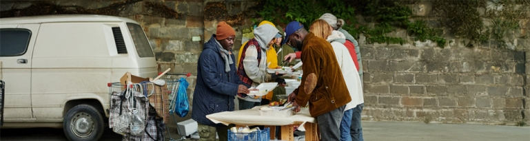 Unhoused people getting food from volunteers.