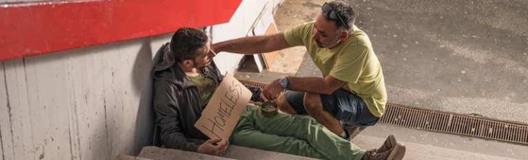 A Polite Man who is Approaching a Unhoused Man who is Sitting on Steps. Kind Man is Helping him by Giving him Support.