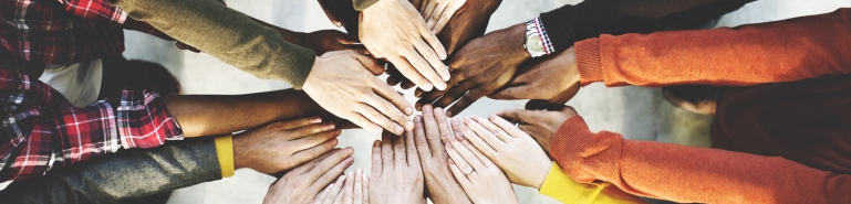 Photo of people of different races hands together in a circle. 
