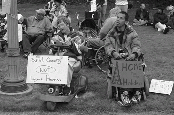 ADAPT protesters at Laguna Honda in 2001 holding sign "Build Community Not Laguna Honda"