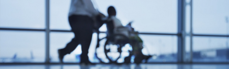 A COVID-19 patient being pushed in a wheel chair at a hospital.