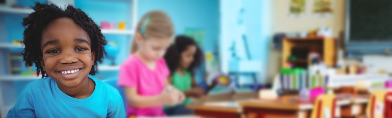 Photo of a Black student in a classroom. Other students are in the background.