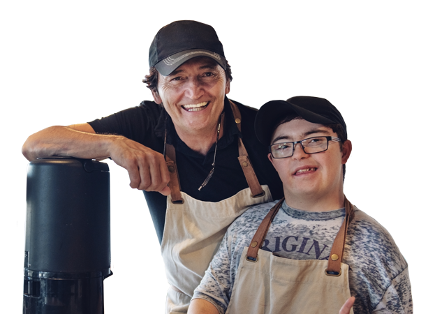A photo of a developmentally disabled person next to his boss. They are at a bakery where they work.