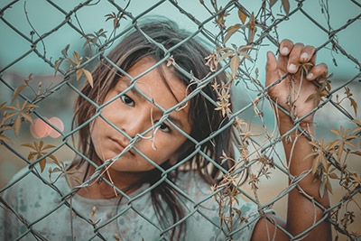 Photo of a young girl behind a fence in a detention facility.