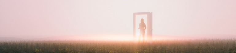 Mujer caminando por una puerta misteriosa en medio de un gran campo de flores.