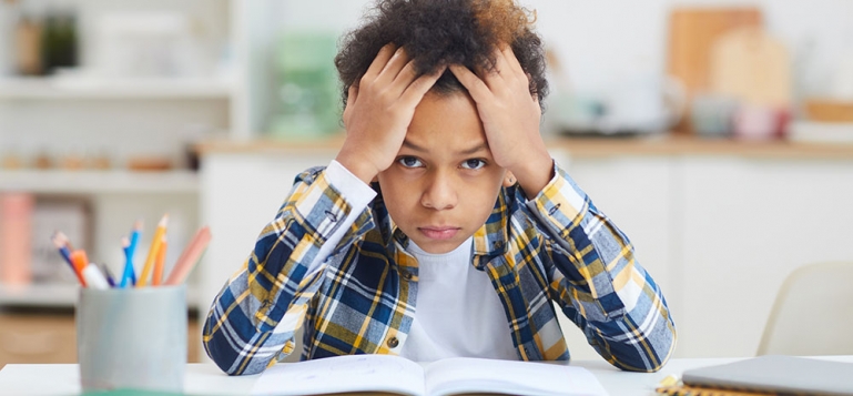 A young child doing his homework. He is frustrated because he is having a difficult time understanding it.