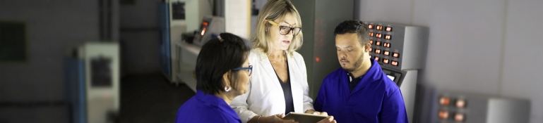 An employee with a disability working with two other employees at a computer lab.