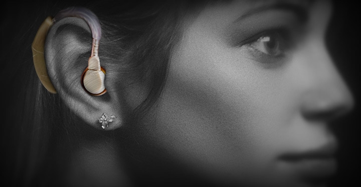 A close up black and white photo of the side of a woman's face with a hearing aid in her ear.