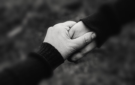 Close of of two hands holding each other in a caring way