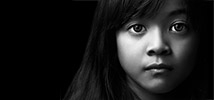Closeup of the face of a young latino girl. She has a very sad look on her face.