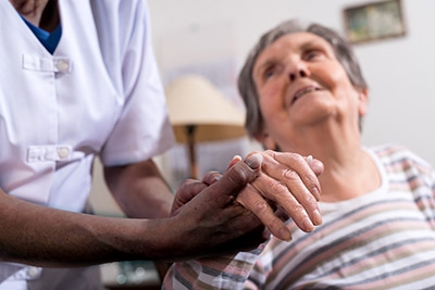 African American woman holding hand of an elderly woman with disabilities