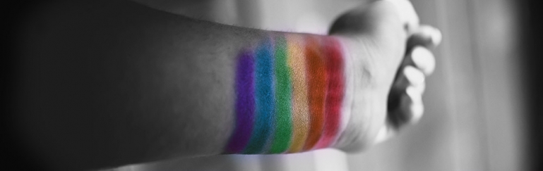 Photo of a persons arm extended with the LBTGQ colors painted on their wrist.