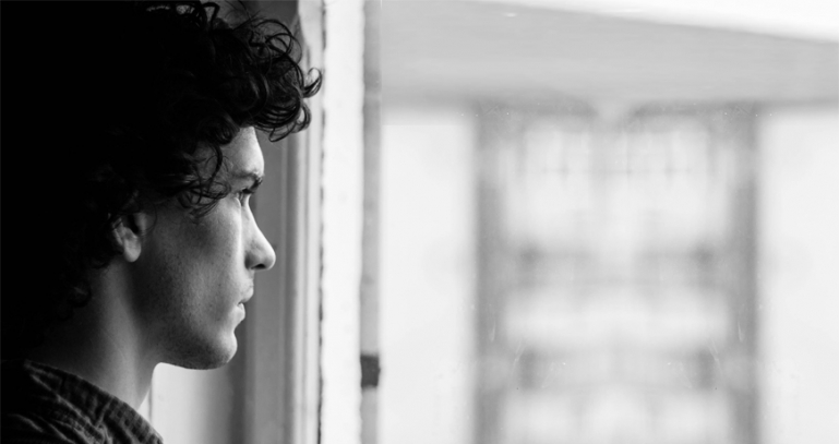 Man with a lonely look on his face looking out a window Man with a lonely look on his face looking out a window