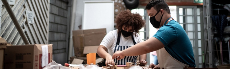 Two people with a disability working in a small packing factory.