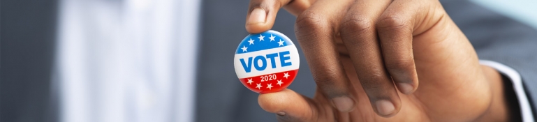 Photo of man's hand holding up a voting pin.