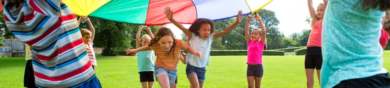 Outdoor Games Children playing a game with a colourful Parachute Child Stock Photo