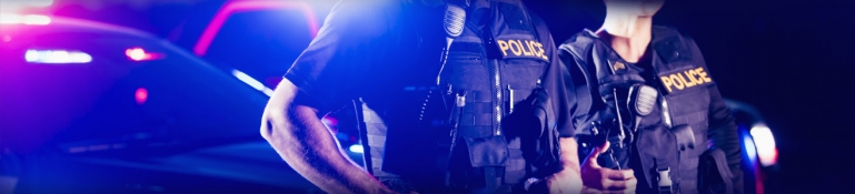 Two police officers standing by their vehicle at night