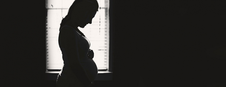 Silhouette of a pregnant woman in front of a window.