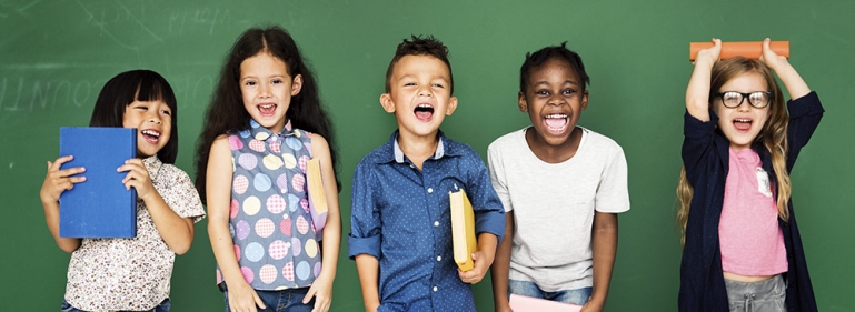 Photo of five happy students in front of a chalk board.