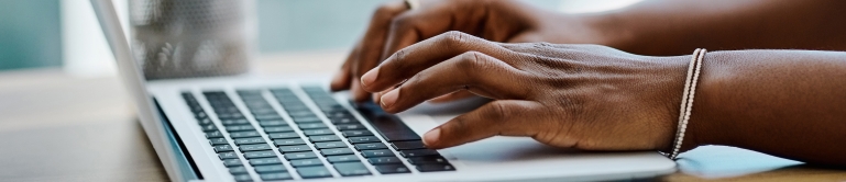 Close up of a woman's hands typing on a laptop.