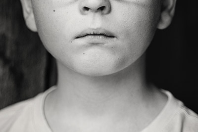 Photo of a sad young boy's face. Image is cropped so you see below his eyes.