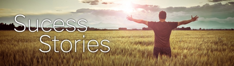 Success Stories - A man in a field with his arms up in the air.