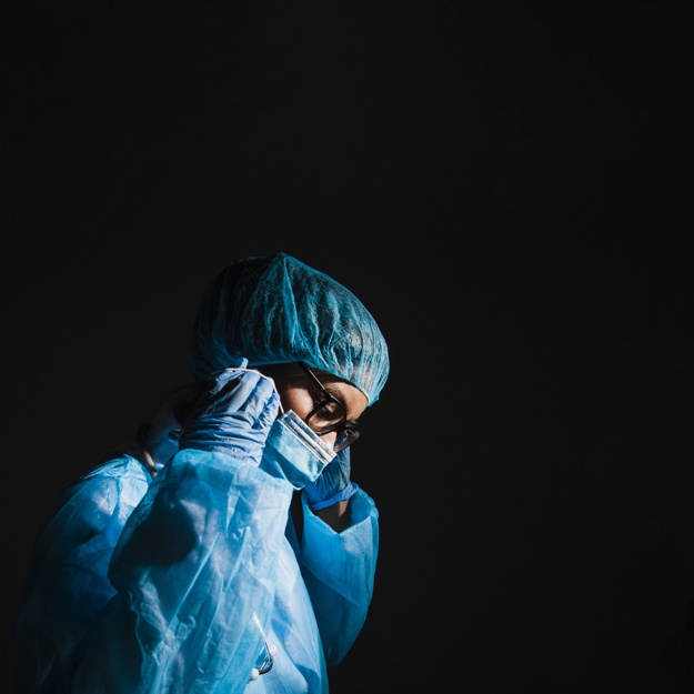 Stock Photo: Ominous photo of a surgeon wearing a mask in a pitch dark room.
