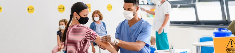 Photo of doctor helping giving a COVID vaccine to a woman.