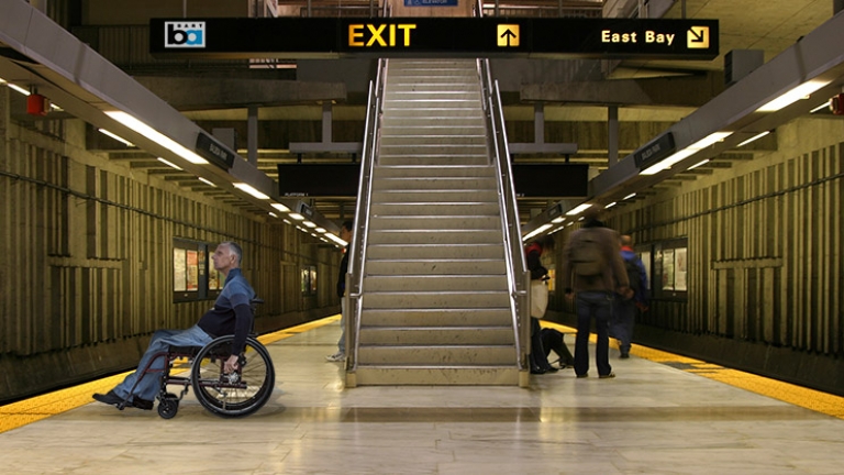 Photo of man in wheelchair waiting for a BART train at a station