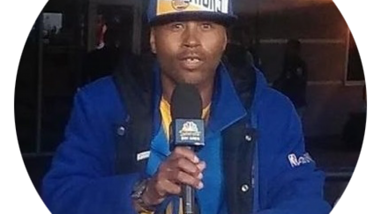 Photo of JH speaking into a microphone.