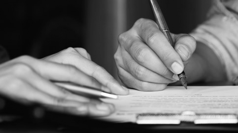 A Black and White closeup photo of a bill being signed.