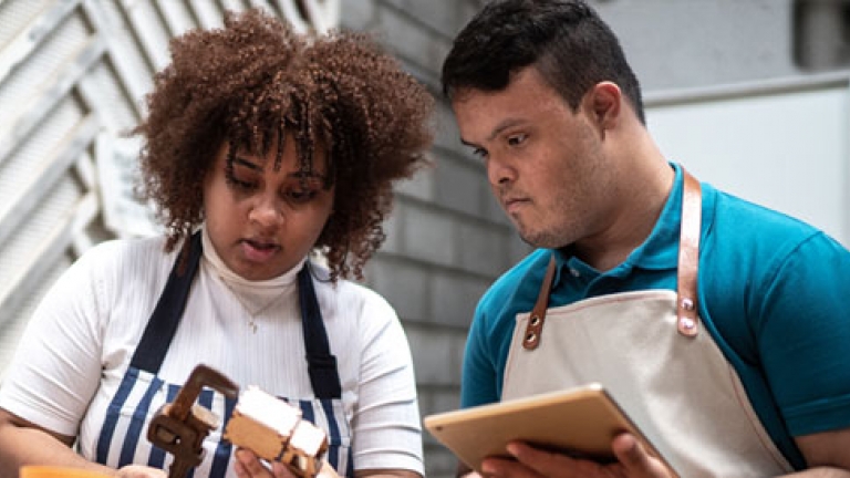 Photo of two adults with a disability working in a warehouse.