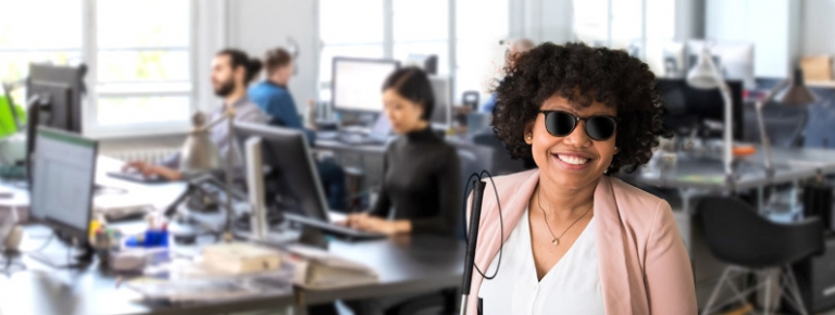 Photo of a woman who is blind working in a business office.