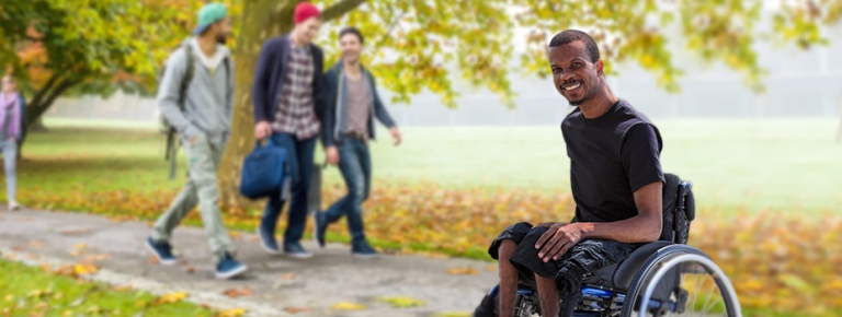 A young man on a college campus. He has a disability and is in a wheel chair.